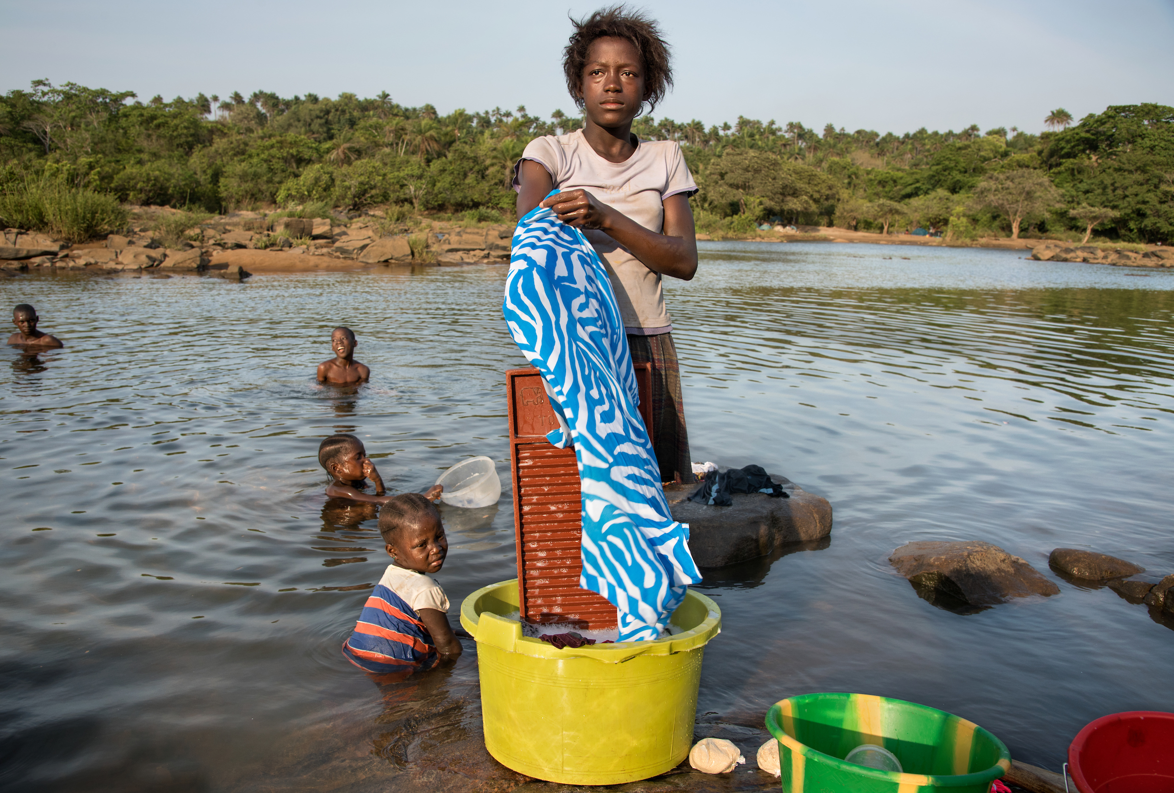 Adolescent girls wash clothes with family members in the town of Mange Bureh, Sierra Leone.