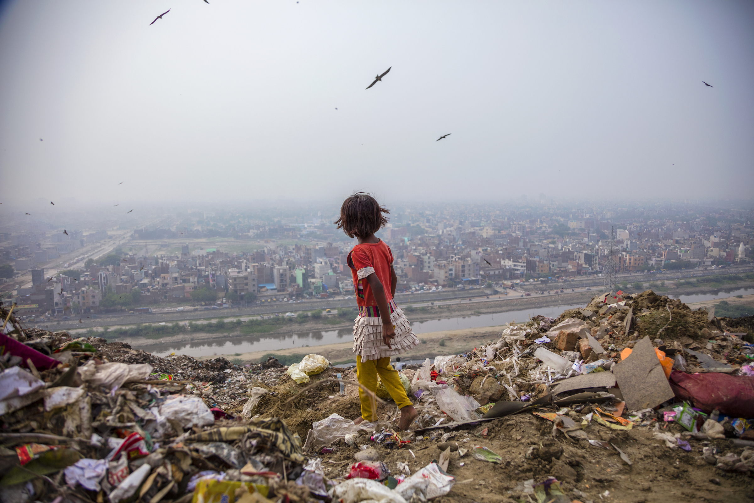 Ghazipur landfill, 70 acres of trash in Delhi, India, provides a hunting ground for 7-year-old Zarina, who salvages items to sell.