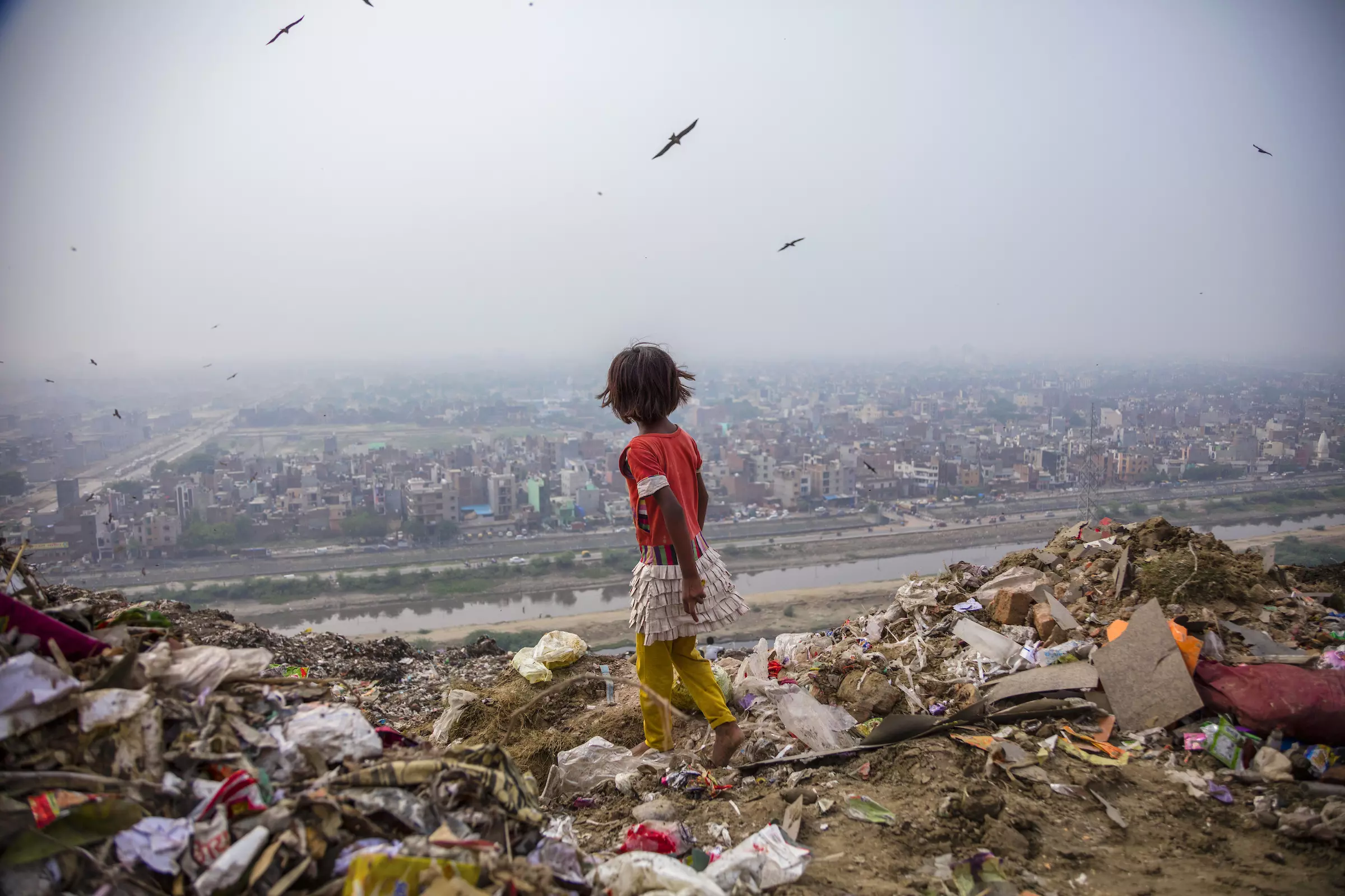 Ghazipur landfill, 70 acres of trash in Delhi, India, provides a hunting ground for 7-year-old Zarina, who salvages items to sell.