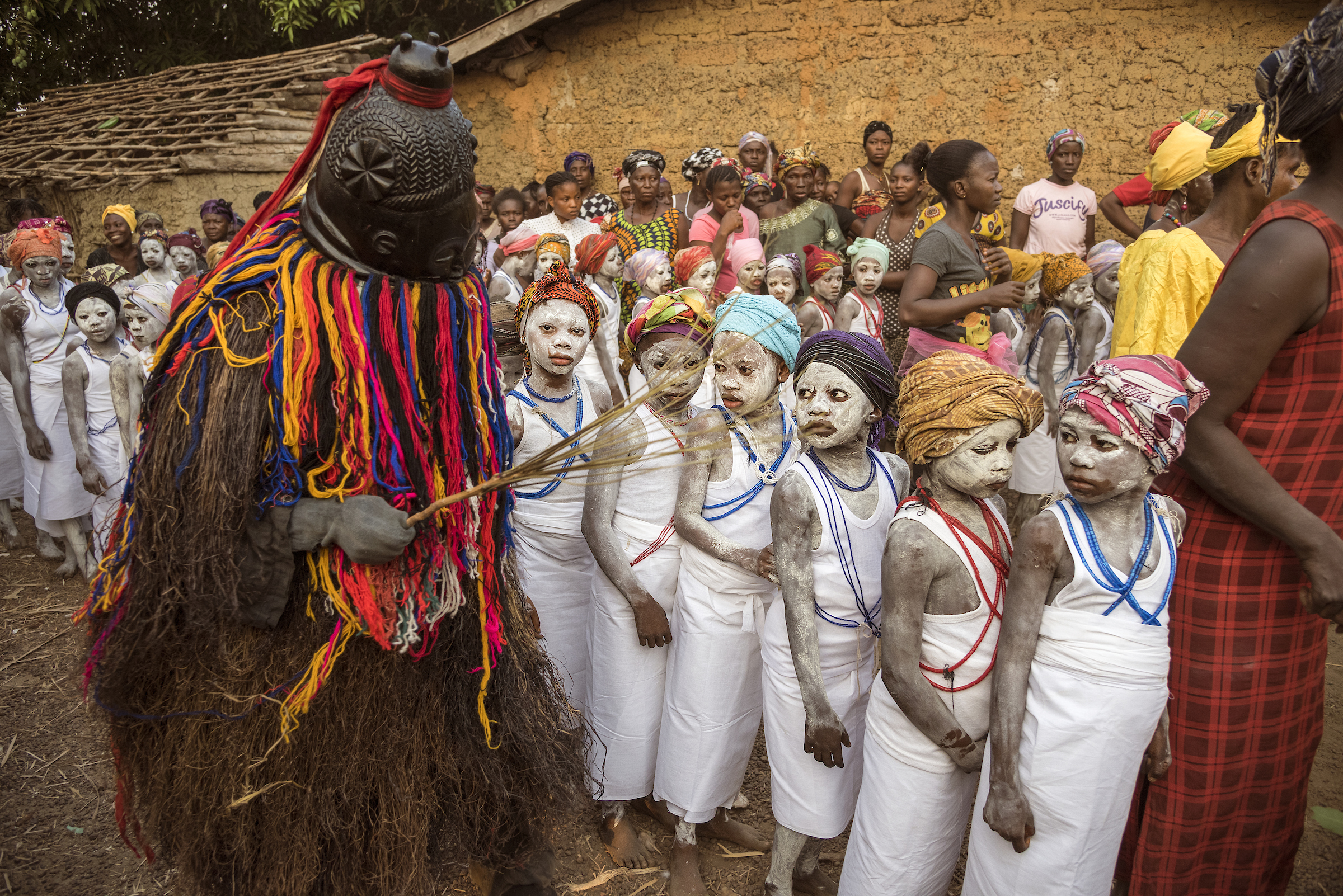 A woman known as the Bondo devil, a high authority in the secret society, participates in the ceremony signifying the community acceptance of this alternative rite of passage.
