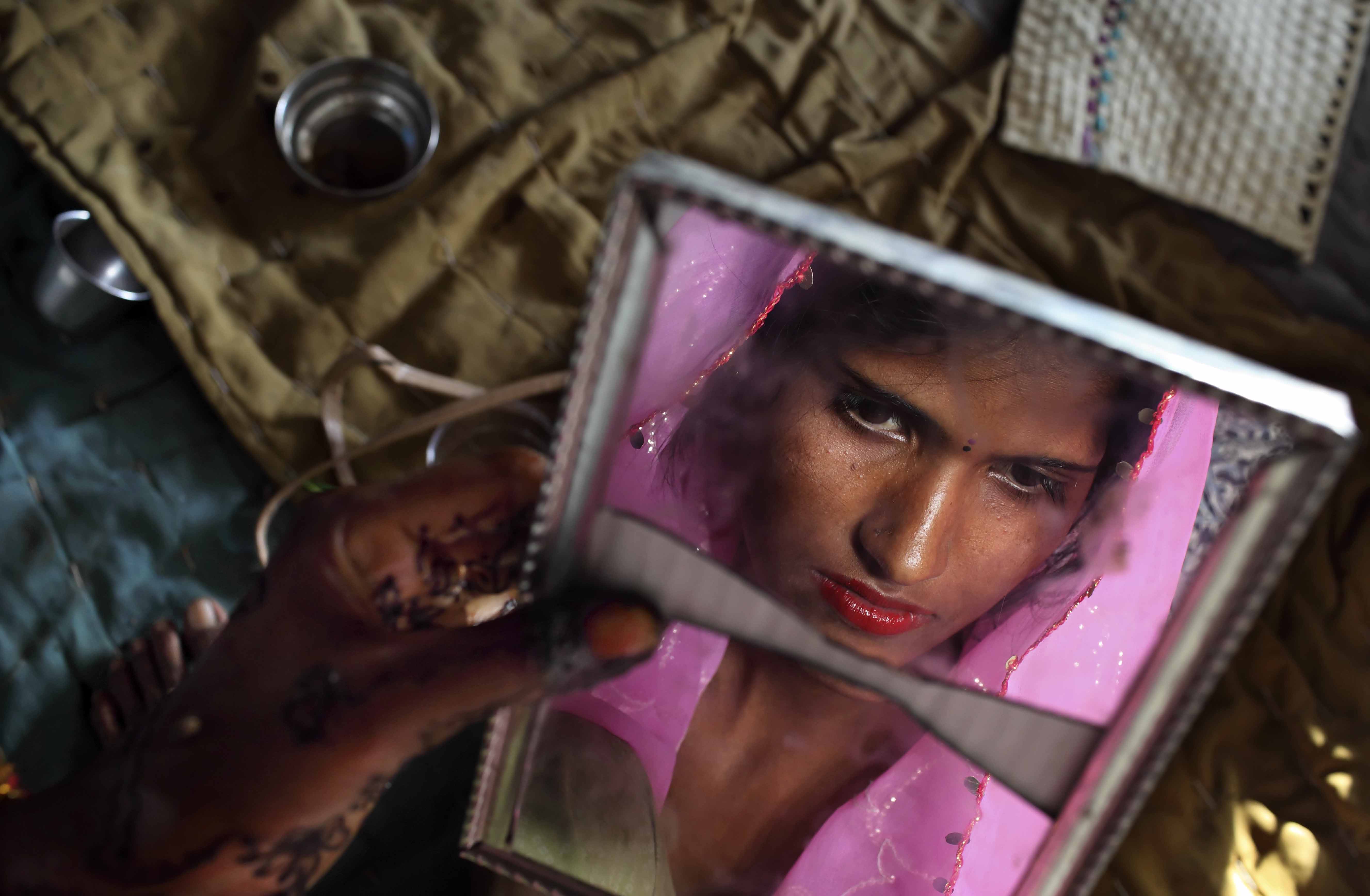 Radha, 15, observes herself in a cracked mirror the day before her wedding. Three young sisters Radha and her two younger sisters were married to three young sibling grooms on the Hindu holy day of Akshaya Tritiya in North India.